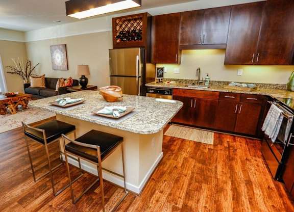 A kitchen with a granite countertop and wooden floors.