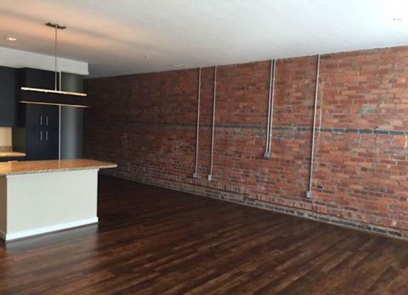 A room with a wooden floor and a brick wall.