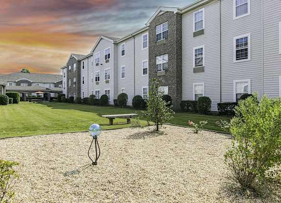 A residential area with apartment buildings and a bench in the foreground.