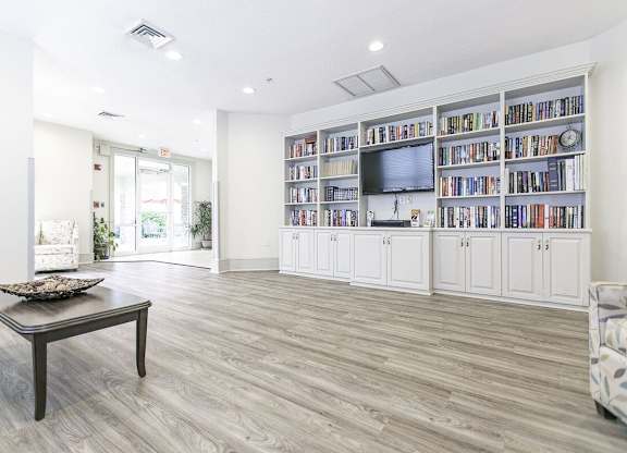 A living room with a wooden floor and a bookshelf filled with books.