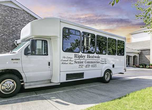 A white bus with the words "Ripley Heatwole Senior Communities" on the side is parked in front of a building.