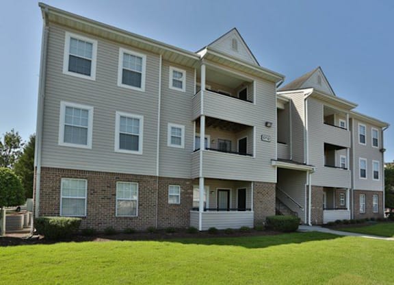 A large apartment building with a grassy front yard.