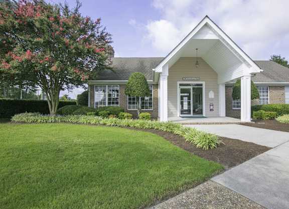 A house with a well-manicured lawn and a tree with pink flowers in front.