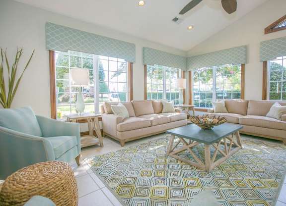 A living room with a large rug and a glass coffee table.