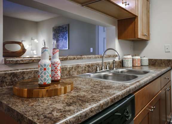 A kitchen with a sink, a cutting board, and a countertop.