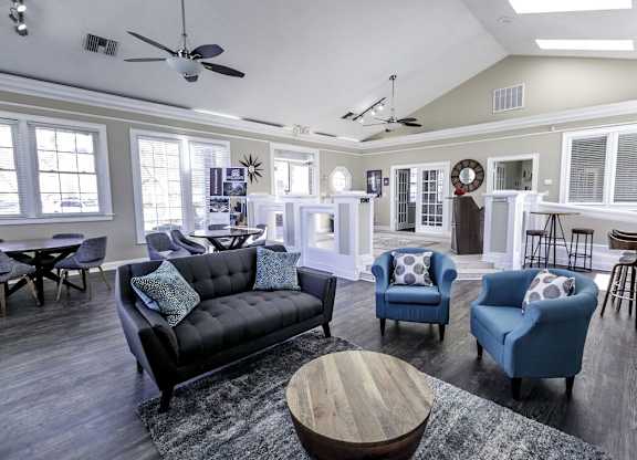 A living room with a black couch, blue chairs, and a wooden coffee table.