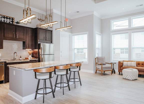 A kitchen with a bar and stools in front of it.