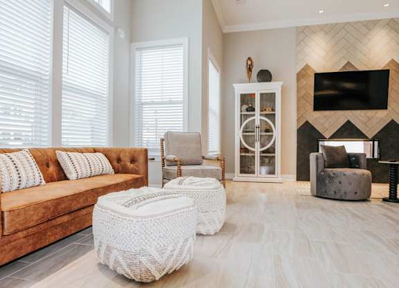 A living room with a brown couch and a white ottoman.