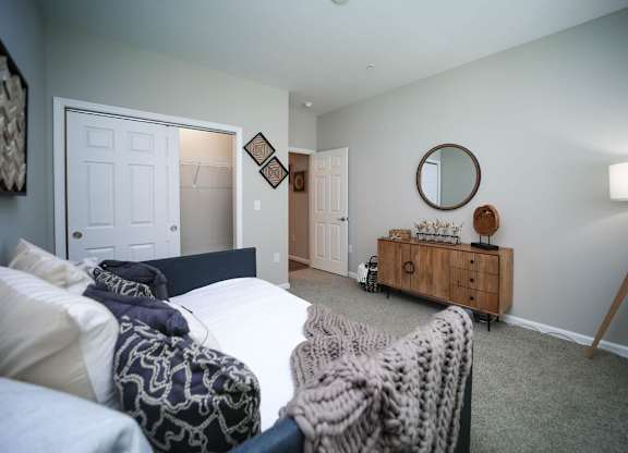 A bedroom with a bed, a dresser, and a lamp.