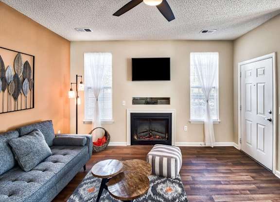 A living room with a grey couch, a fireplace, and a television mounted above it.