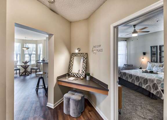 A bedroom with a bed, a desk with a chair, and a mirror on the wall.