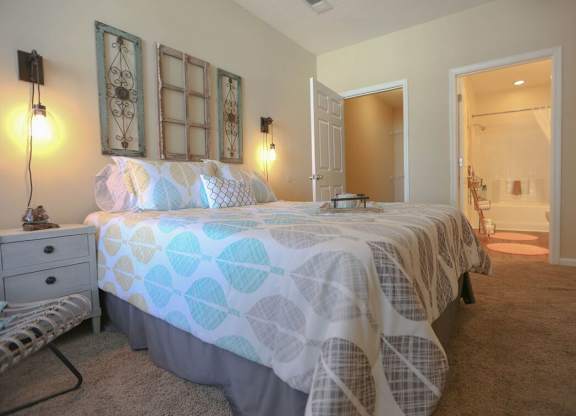 A bedroom with a bed, dresser, and two wall lamps.