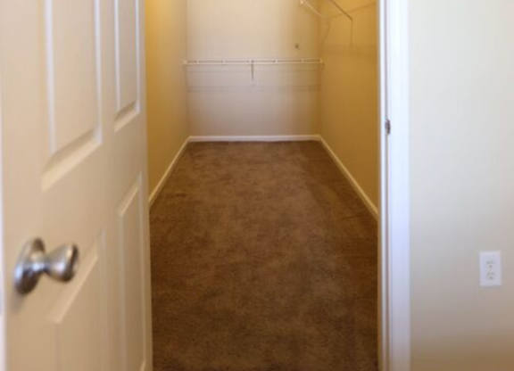 A white door is open to a hallway with a carpeted floor.