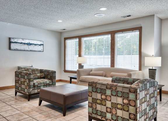 A living room with a couch, chair, ottoman, and lamp.