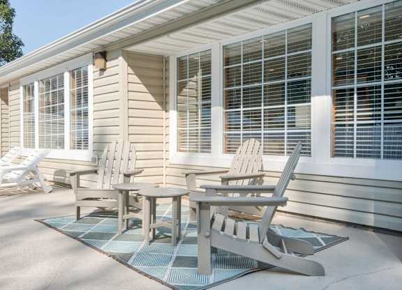 A patio with a table and chairs is in front of a house.