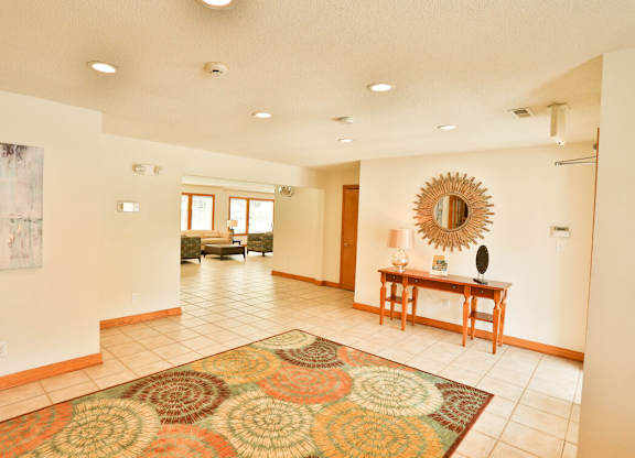 A large room with a rug on the floor and a mirror on the wall.