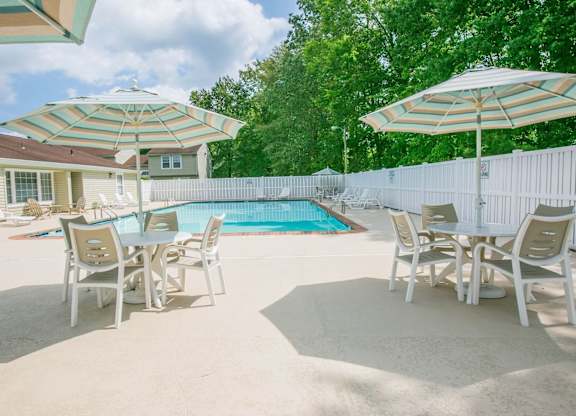 A poolside table set with chairs and umbrellas.
