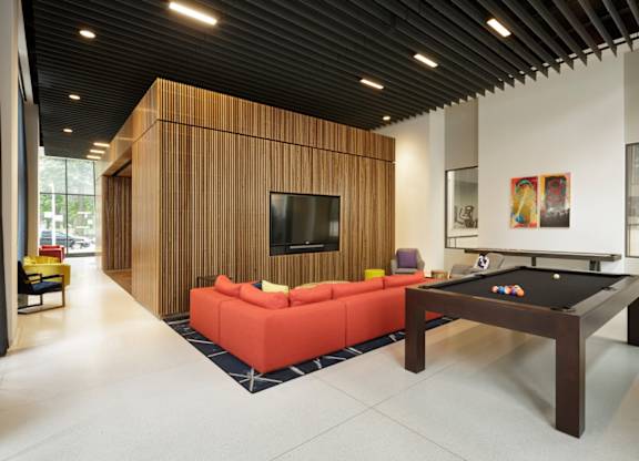 A billiard table is in the middle of a room with a couch and a television.