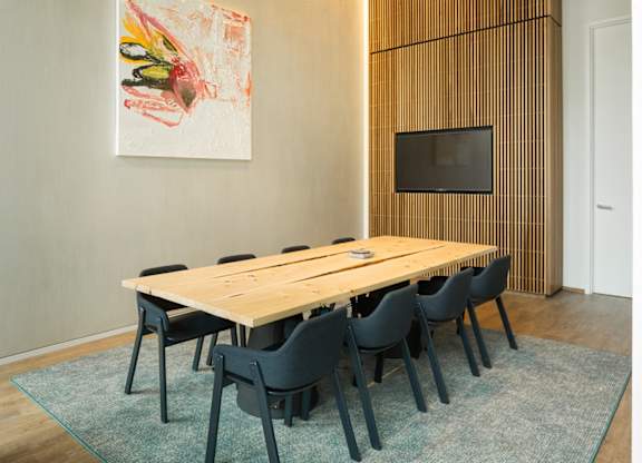 A painting hangs on the wall above a wooden table with chairs.