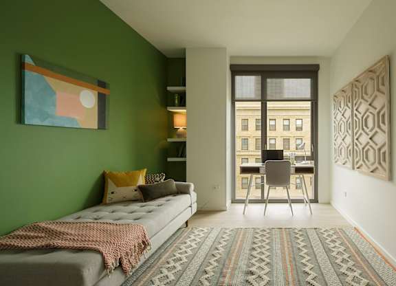 A bedroom with a bed and a chair in front of a window.