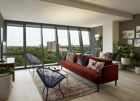 A living room with a red couch and a view of the city.