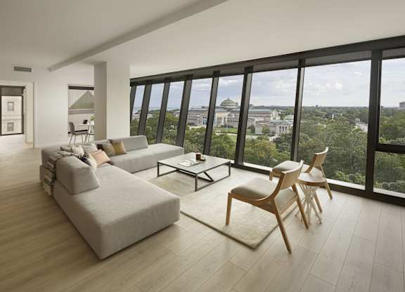A living room with a couch, chairs, and a view of the city.