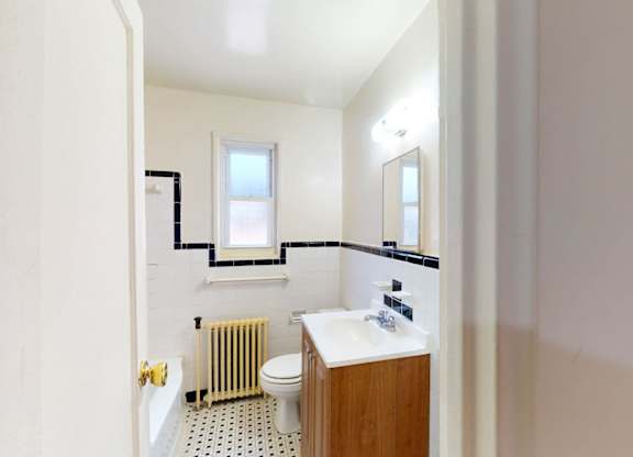 A bathroom with a toilet, sink, and window.