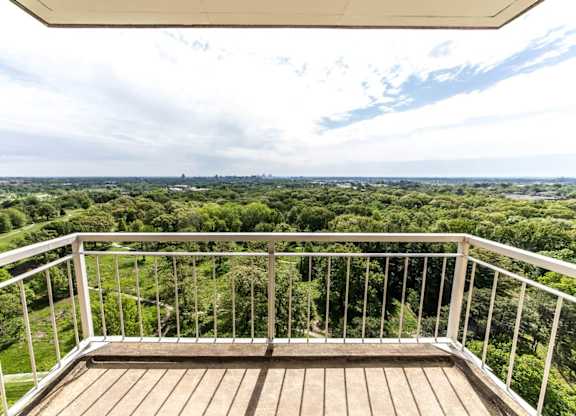 A balcony with a view of a green landscape.