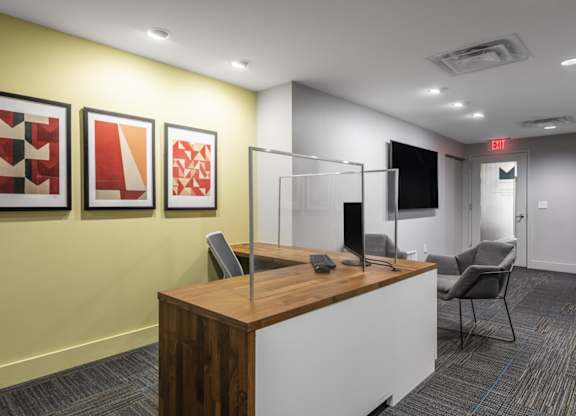 A reception area with a wooden desk and three framed artworks on the wall.