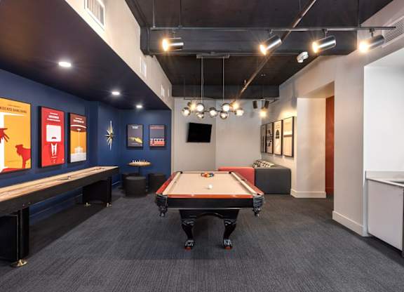 A pool table is in the middle of a room with a blue wall and a TV.