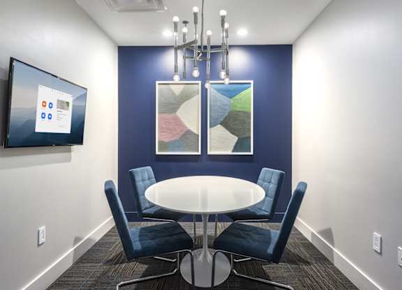 A conference room with a table, chairs, and a screen on the wall.