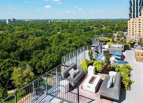 A balcony with a table and chairs overlooks a lush green forest.