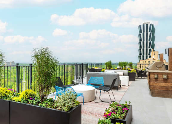 A rooftop patio with a table and chairs overlooking a cityscape.