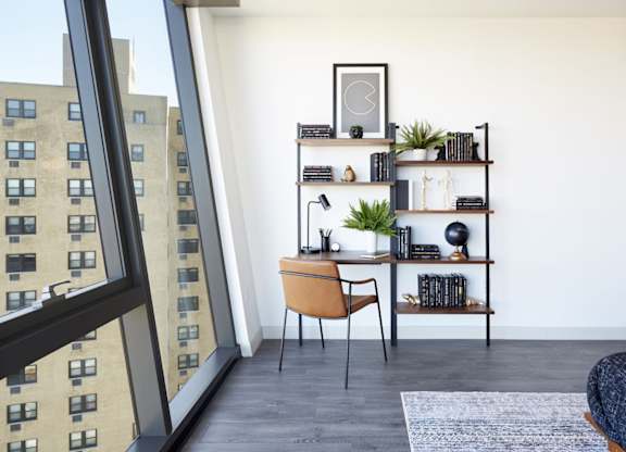A room with a desk, chair, and shelves with various items.