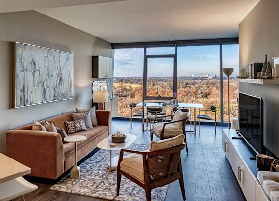 A living room with a couch, chairs, and a painting on the wall.