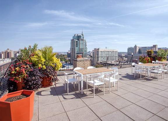 A rooftop patio with a table and chairs overlooking a city skyline.