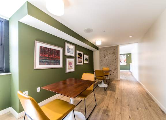 A room with a green wall and a wooden table with chairs.