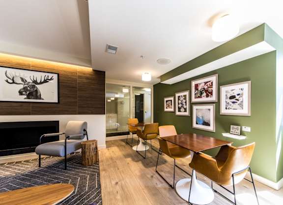 A room with a fireplace, chairs, and pictures on the wall.
