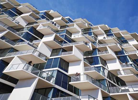A modern building with white and blue balconies against a blue sky.