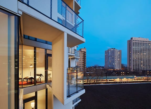 A modern building with a balcony overlooking a cityscape at dusk.