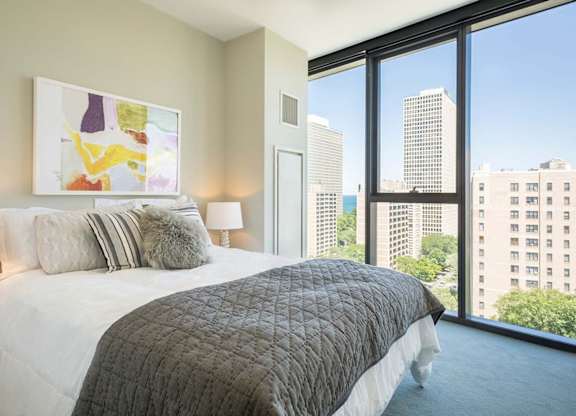 A bedroom with a large bed and a view of the city.