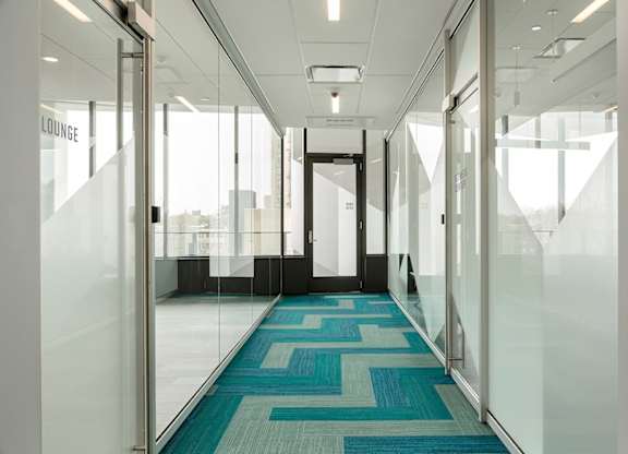 A hallway with glass walls and a blue carpet.