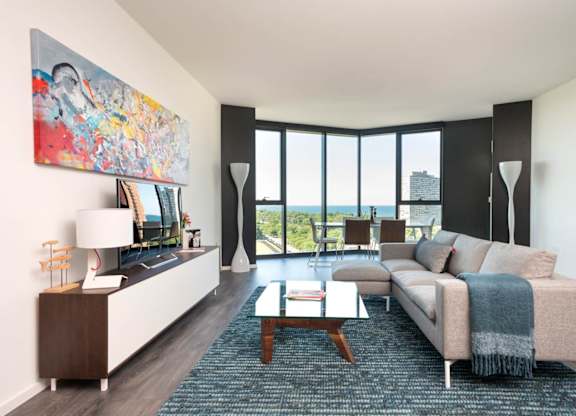 A living room with a couch, a coffee table, and a large painting on the wall.
