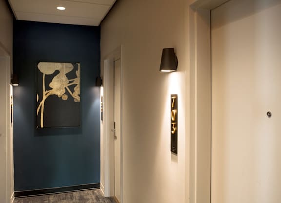 A hallway with a blue wall and a picture of a chair.