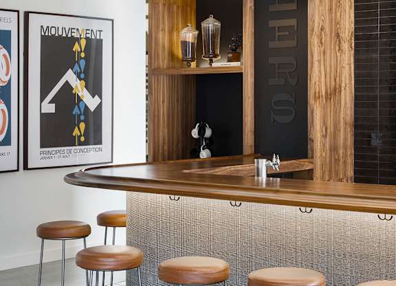 A bar with a wooden shelf and a black and white poster on the wall.