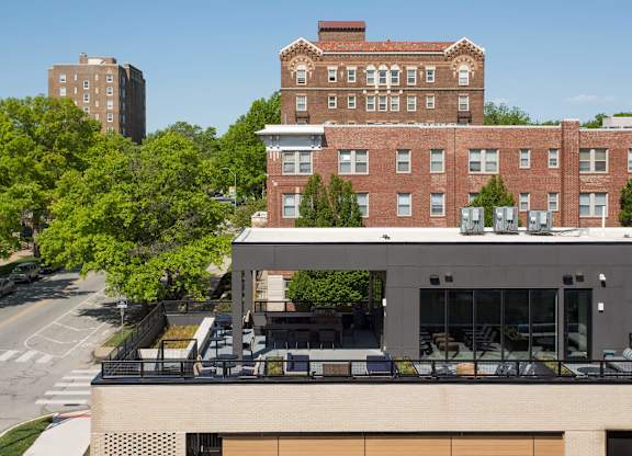 A modern building with a balcony is in front of a red brick building.