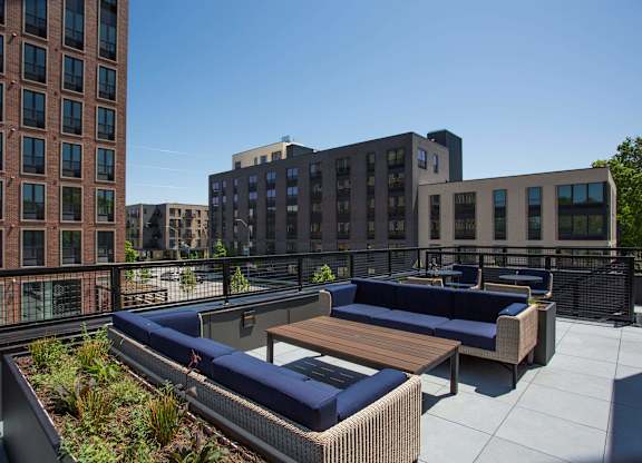 A rooftop patio with a couch and a table.