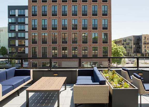 A large red brick building with a balcony containing a table and chairs.