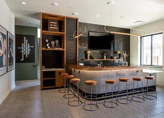 A modern bar area with a dark counter and stools.