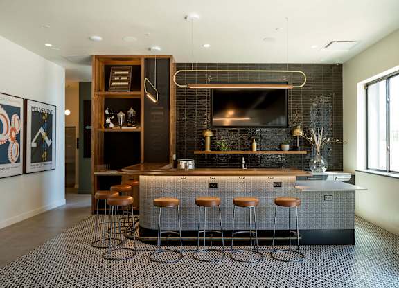 A modern kitchen with a bar area and stools.